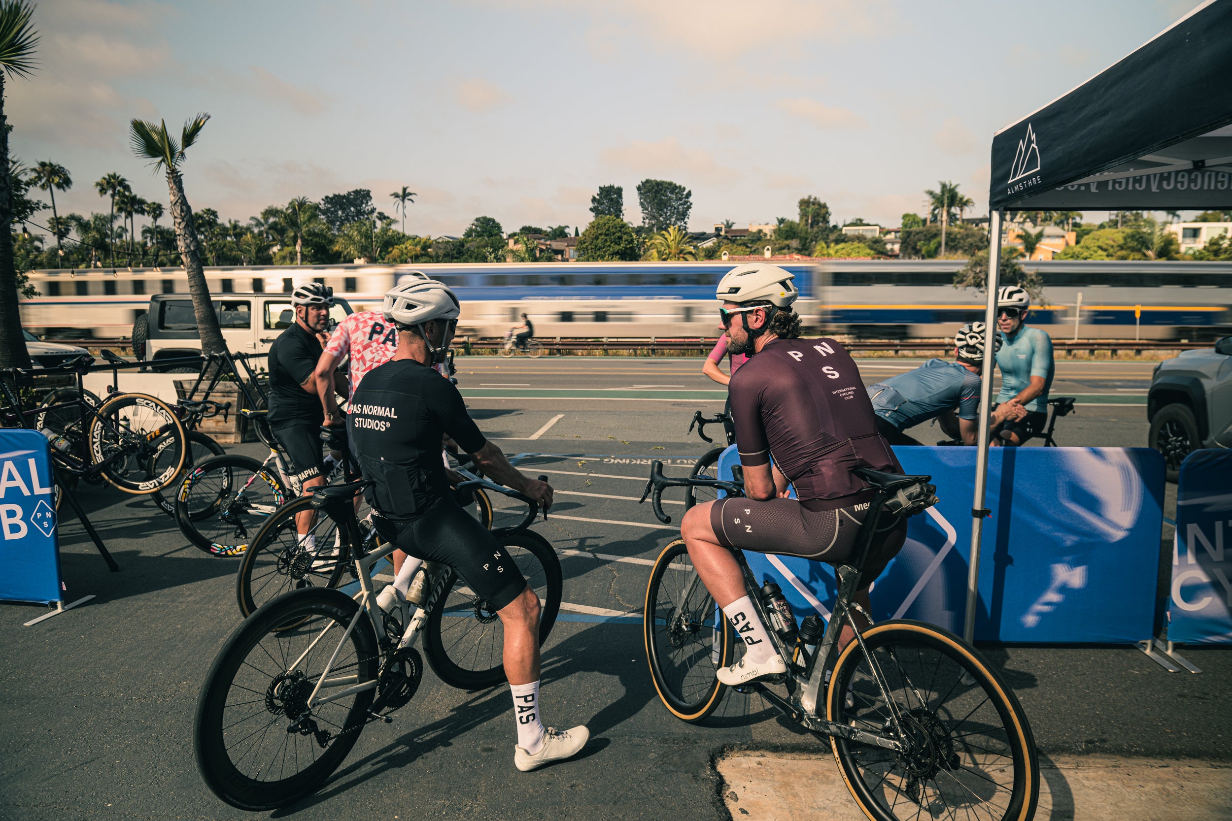 Bikers preparing for a group road cycling ride in encinitas with palm trees and a clear sky in the background.