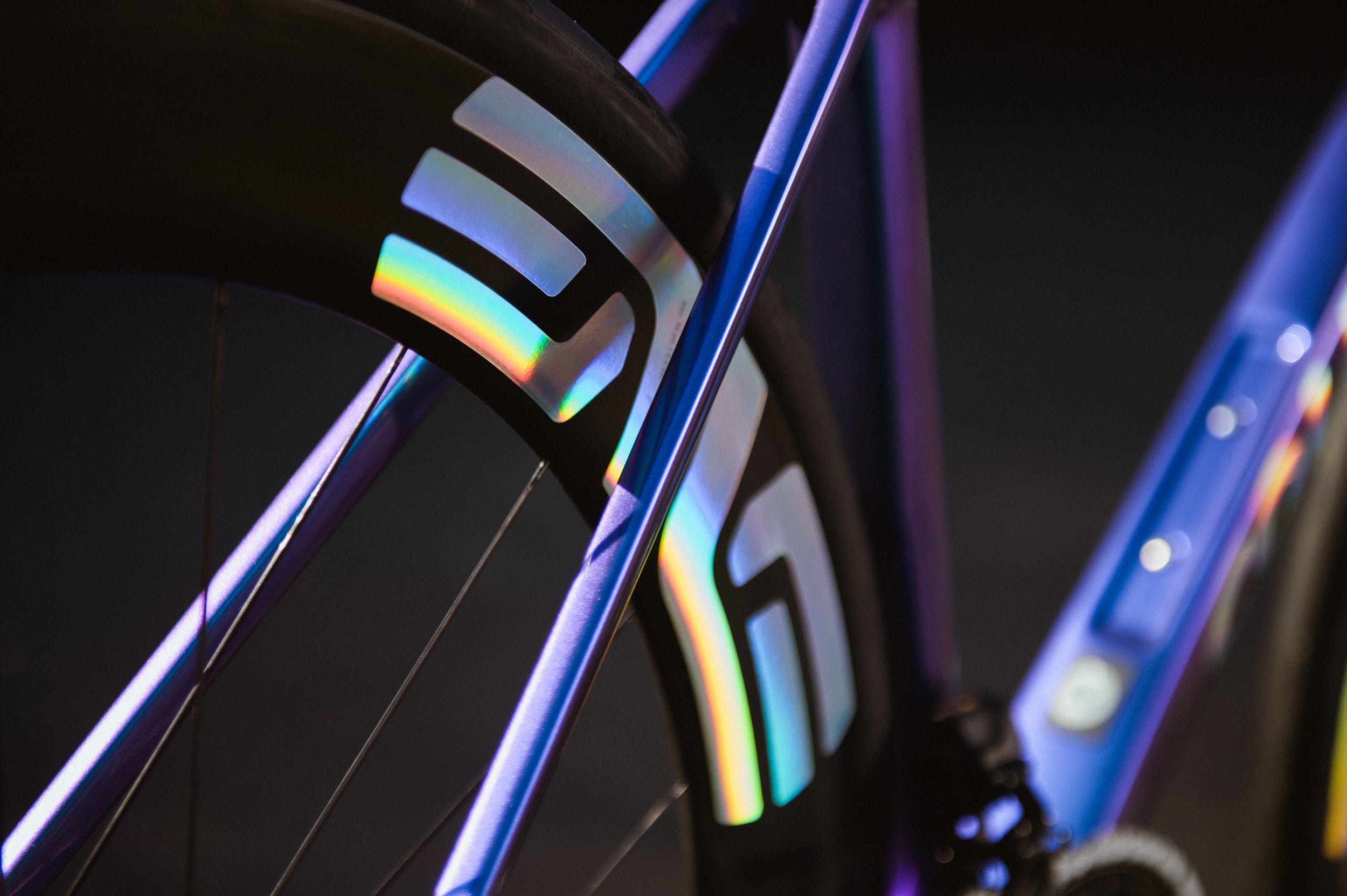 Close-up of a bicycle wheel with colorful rim design on a dark background, Enve Composites premium road cycling wheels.